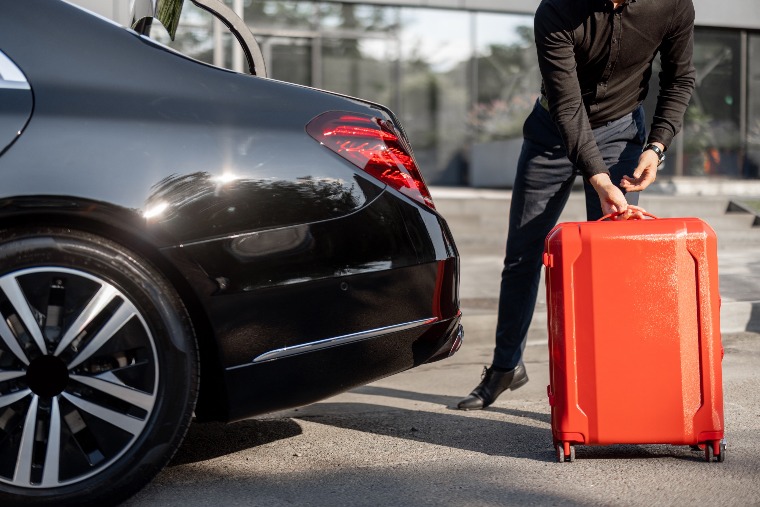 Chauffeur preparing luggage beside an executive vehicle